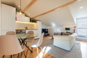 Sacramento Terrace Apartment في لشبونة: غرفة معيشة مع طاولة زجاجية وكراسي بيضاء