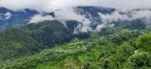 a view of a valley in the mountains with clouds at Hotel Vivek Nomadic in Dalhousie