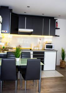 una cocina con armarios negros y una mesa con sillas en Blue Line Apartements, en Arnoldstein