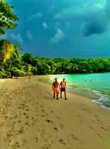 zwei Leute laufen am Strand in der Unterkunft The Beach in Manuel Antonio