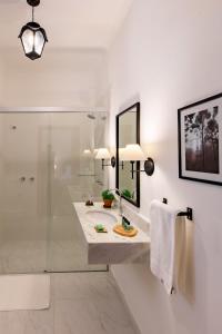 a white bathroom with a sink and a shower at Pousada Vila Alto dos Pinhais in Espirito Santo Do Pinhal