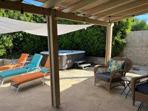 a patio with chairs and a hot tub under a pergola at Bright & Airy Pool-Spa Oasis Home-Dogs Welcome! City of Palm Springs # 4243 in Palm Springs