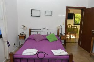 1 dormitorio con 1 cama morada y 2 toallas en La Salamandra. Casa en la Sierra en Tandil