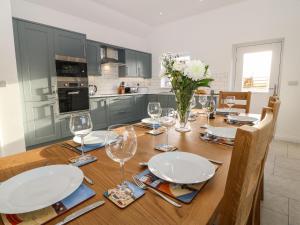 a kitchen with a wooden table with plates and wine glasses at Yr Hen Feudy in Moelfre