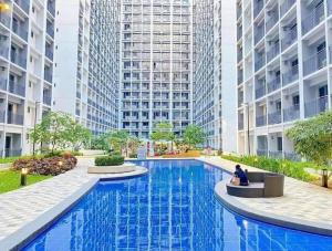 a person sitting on a bench in front of a large building at Deluxe Suites Razelles 2 at Shore 2 Residences Tower 1 in Manila