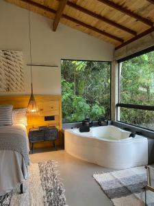 a large bath tub in a bedroom with a bed at Pousada Chácara Aracê in Araras Petropolis