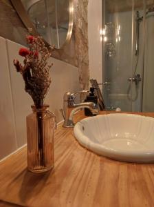a bathroom sink with a vase with flowers in it at La tour du Grand Boust in Longué