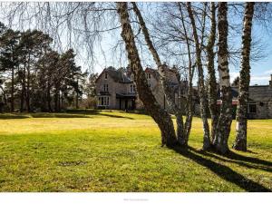 una casa en un campo con árboles en primer plano en Dalrachney Lodge en Carrbridge