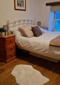 um quarto com uma cama com uma mesa de cabeceira e um tapete branco em Cringley Cottage em Askrigg