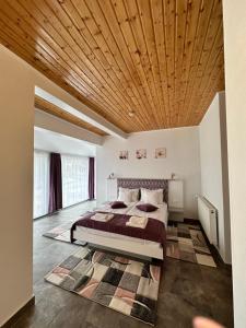 a bedroom with a bed with a wooden ceiling at Red Family Apartments in Păltiniş