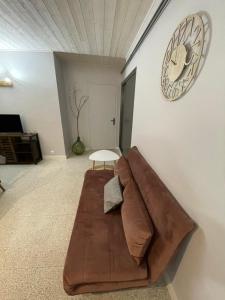 brązowa kanapa w salonie z zegarem na ścianie w obiekcie Vue magnifique w mieście Vernet-les-Bains