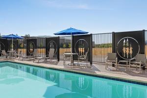 a pool with chairs and umbrellas next to a fence at Holiday Inn Express & Suites - Ukiah, an IHG Hotel in Ukiah
