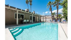 a swimming pool in front of a house with palm trees at Bright & Airy Pool-Spa Oasis Home-Dogs Welcome! City of Palm Springs # 4243 in Palm Springs