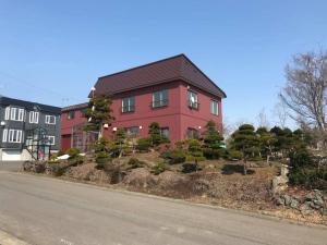 a red house with a garden in front of a street at Rusutsu Washi House in Rusutsu