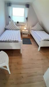 2 Betten in einem kleinen Zimmer mit Fenster in der Unterkunft Haus Luise in Poppenbüll