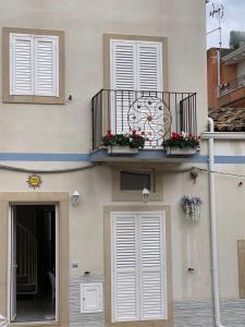 un edificio con orologio e fiori sul balcone di CAPINERA a Pozzallo