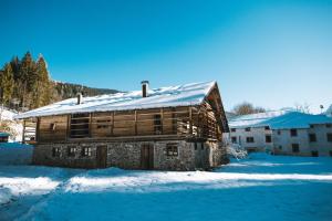 une ancienne cabane en rondins avec de la neige sur le toit dans l'établissement Lärchenwirt Dolomites, à San Nicolò di Comelico