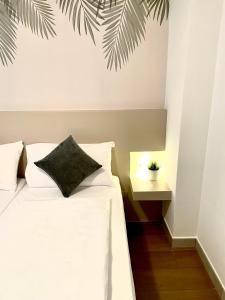 - une chambre avec un lit blanc et une plante sur le mur dans l'établissement Residence Verdeblu, à Arco