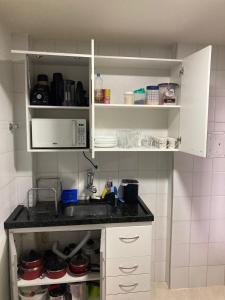 a kitchen with white cabinets and a sink at Conforto - 100 metros do Mar - Ar condicionado nos quartos - Internet- Netflix e Globoplay in Guarapari