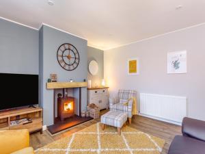 uma sala de estar com lareira e televisão em Parkhill Cottage em Kildary