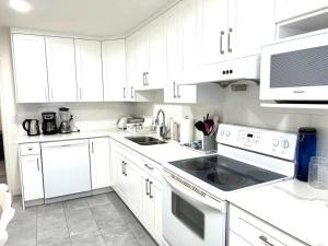 una cucina bianca con armadi bianchi e piano cottura forno superiore di Skytrain 2BR Reno'd ground level fullsuite near Coquitlam Center a Port Coquitlam