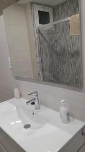 ein Waschbecken mit einem Spiegel und einem Seifenspender in der Unterkunft 150m2 Con vistas al Mar y al Castillo de Cullera in Cullera