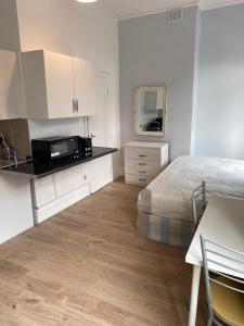 a bedroom with a bed and a kitchen with a microwave at Studio on Finchley Road in London