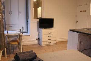 a room with a kitchen with a tv on a dresser at Studio on Finchley Road in London
