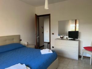 1 dormitorio con 1 cama azul y TV en Home Azzurra, en Capolona