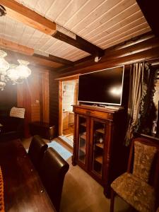 - un salon avec une télévision, une table et des chaises dans l'établissement Chalet PJagodic, à Cerklje na Gorenjskem