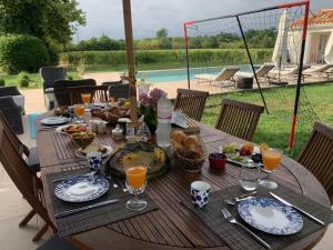 a wooden table with plates of food and glasses of orange juice at Charmante Chambre d’hôtes Domaine-de-la-terrasse SAS et Gite ANDA - Montauban, Alba-Sud (qualité) in Lacourt-Saint-Pierre