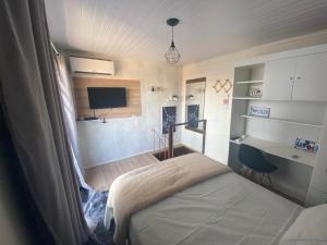um pequeno quarto com uma cama e uma televisão em Moradas Desterro, próximo ao aeroporto 06 em Florianópolis