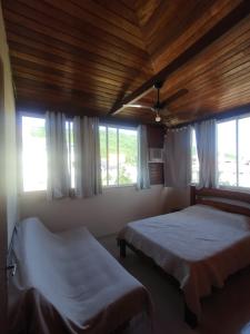 a bedroom with two beds and two windows at Apart da Cachoeira in Florianópolis