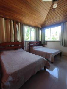 two beds in a room with two windows at Apart da Cachoeira in Florianópolis