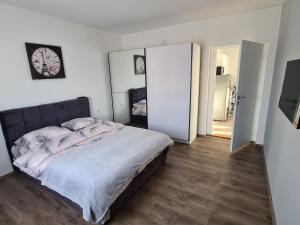 1 dormitorio con 1 cama y reloj en la pared en Grey & Sunny Apartments Zaječar, en Zajecar