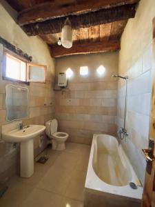 a bathroom with a tub and a toilet and a sink at Siwa Desert Home in ‘Izbat Ţanāţī