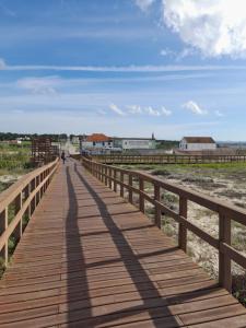 a wooden boardwalk on the beach with a person walking on it at Sea, Sun and Wild Nature in Costa de Santo André