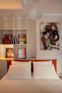 a bedroom with a bed with white sheets and paintings at una stanza in carmine in Brescia