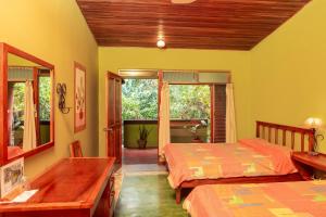1 dormitorio con 2 camas, mesa y ventanas en Lake Arenal Brewery & Hotel, en Tilarán