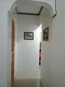 a hallway with a white wall with two pictures on it at Meghan’s Homestay in General Luna