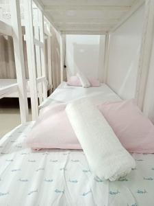 een slaapkamer met een bed met roze en witte lakens bij Meghan’s Homestay in General Luna