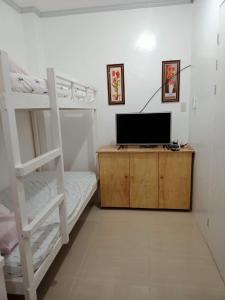 een slaapkamer met 2 stapelbedden en een televisie bij Meghan’s Homestay in General Luna