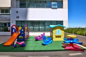 plac zabaw z różnymi rodzajami sprzętu do zabawy przed budynkiem w obiekcie Apart-hotel América B w mieście Campos dos Goytacazes