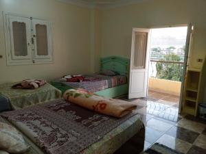 a room with three beds and a balcony at Go Inn Backpackers in Aswan