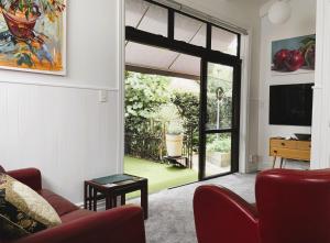 a living room with a red couch and a sliding glass door at The Partchery Devonport in Auckland