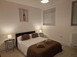 a bedroom with a bed with two tables and two windows at Cosy 2 Bedroom Apartment by ReeAni Stays with Wifi, Netflix & Private Parking in Uxbridge