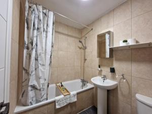 a bathroom with a shower curtain and a sink and a tub at zDNU 2 Bedroom Apartment ReeAni Stays in Uxbridge