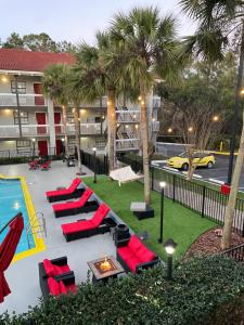 una piscina en un hotel con sillas rojas y palmeras en Casa Bella Inn & Suites Extended Stay en Tallahassee