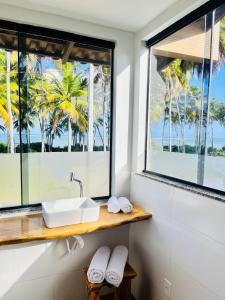 佩德拉斯港的住宿－Pousada Iandê Patacho，一间带水槽的浴室和一个带棕榈树的窗户。