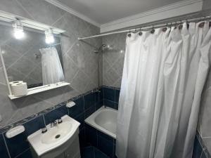 a bathroom with a white shower curtain and a sink at Hosteria Yamile in El Calafate +39 photos